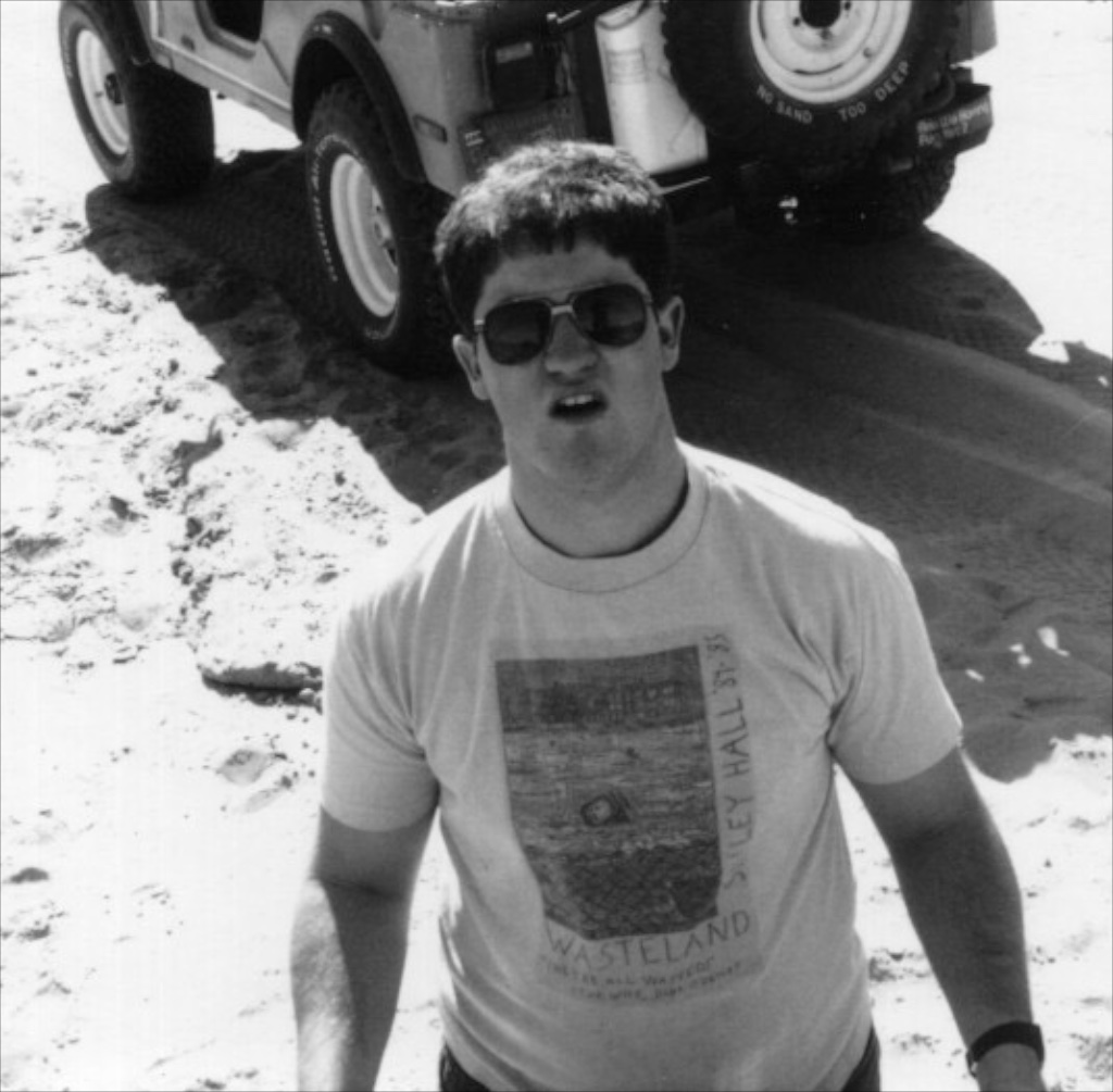 Fred with his 1976 Jeep CJ5 in the dunes. The spare reads: "No hill too steep, no sand too deep."